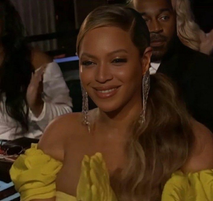 a woman in a yellow dress sitting next to other people at a table and - Is Beyoncé Pregnant In 2025? Speculation And Clues